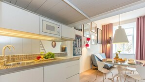 A modern kitchen with a built-in microwave, a stainless steel sink, and a wooden countertop. There is a dining area with a glass table and white chairs. - Tromostovje III at Triple Bridge Ljubljana, Ljubljana, Slovenia (Ljubljana)