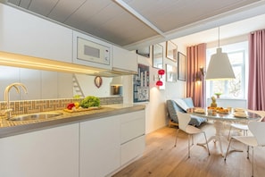 Une cuisine moderne dotĂ©e dâun four Ă micro-ondes encastrĂ©, dâun Ă©vier en acier inoxydable et dâun plan de travail en bois.