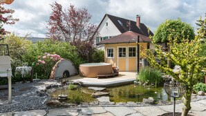 A house with a hot tub, a pond, and a stone pathway. - Comfortable 4-Star Vacation Apartment "Wolf" with Terrace, Grill & Wi-Fi (Überlingen)