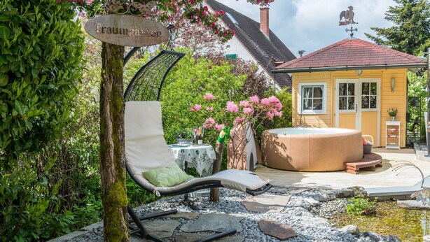 A garden with a lounge chair, a hot tub, and a sign that reads 'Traumgarten.' - Comfortable 4-Star Vacation Apartment "Wolf" with Terrace, Grill & Wi-Fi (Überlingen)