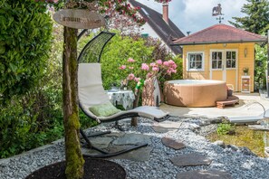 Un jardin avec un fauteuil de relaxation, un jacuzzi et un panneau indiquant « Traumgarten ».