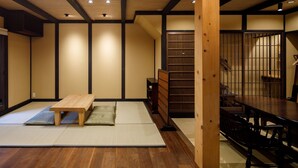 A traditional Japanese room with tatami flooring, a low wooden table, and a sliding door leading to a dining area.