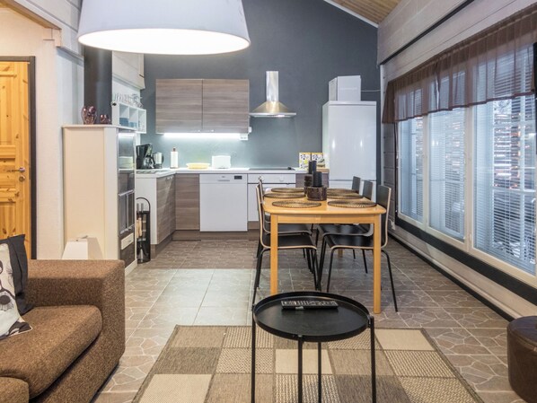 Un espace de vie compact comprenant une kitchenette, un coin repas et une vue sur la ville grâce à de grandes fenêtres.