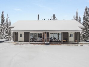 A building with a snow-covered roof, large windows, and a bicycle parked outside.