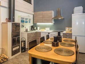 A modern kitchen with a dining area, equipped with a stove, refrigerator, and various kitchen appliances.