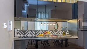 Cozinha moderna com ilha central, forno embutido e janela com cortinas.