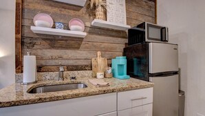 A kitchen with a granite countertop, stainless steel sink, white cabinets, a microwave, and a refrigerator. - Greers Ferry Lakefront Getaway - easy lake access (Higden)