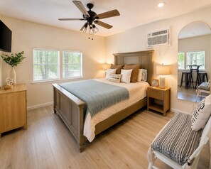 A bedroom with a bed, bedside tables, a chair, a ceiling fan, and a window. - Greers Ferry Lakefront Getaway - easy lake access (Higden)