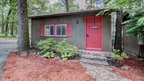 A small cabin with a red door, a window with shutters, and a stone pathway leading to the entrance. - Greers Ferry Lakefront Getaway - easy lake access (Higden)
