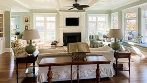 A spacious living room with a fireplace, comfortable seating, and large windows.