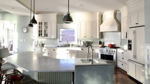 A spacious kitchen with white cabinetry, a large island, and modern appliances.