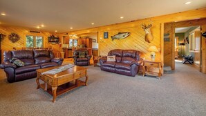 A log cabin interior with leather sofas, a wooden coffee table, and a deer head mounted on the wall. - Clarks Fork Crossing- Direct River Access, Large family Cabin! (Cody)
