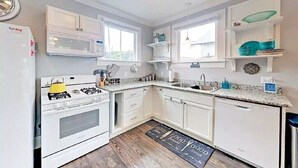 A compact kitchen with white cabinets, a built-in microwave, a gas stove, and a sink.