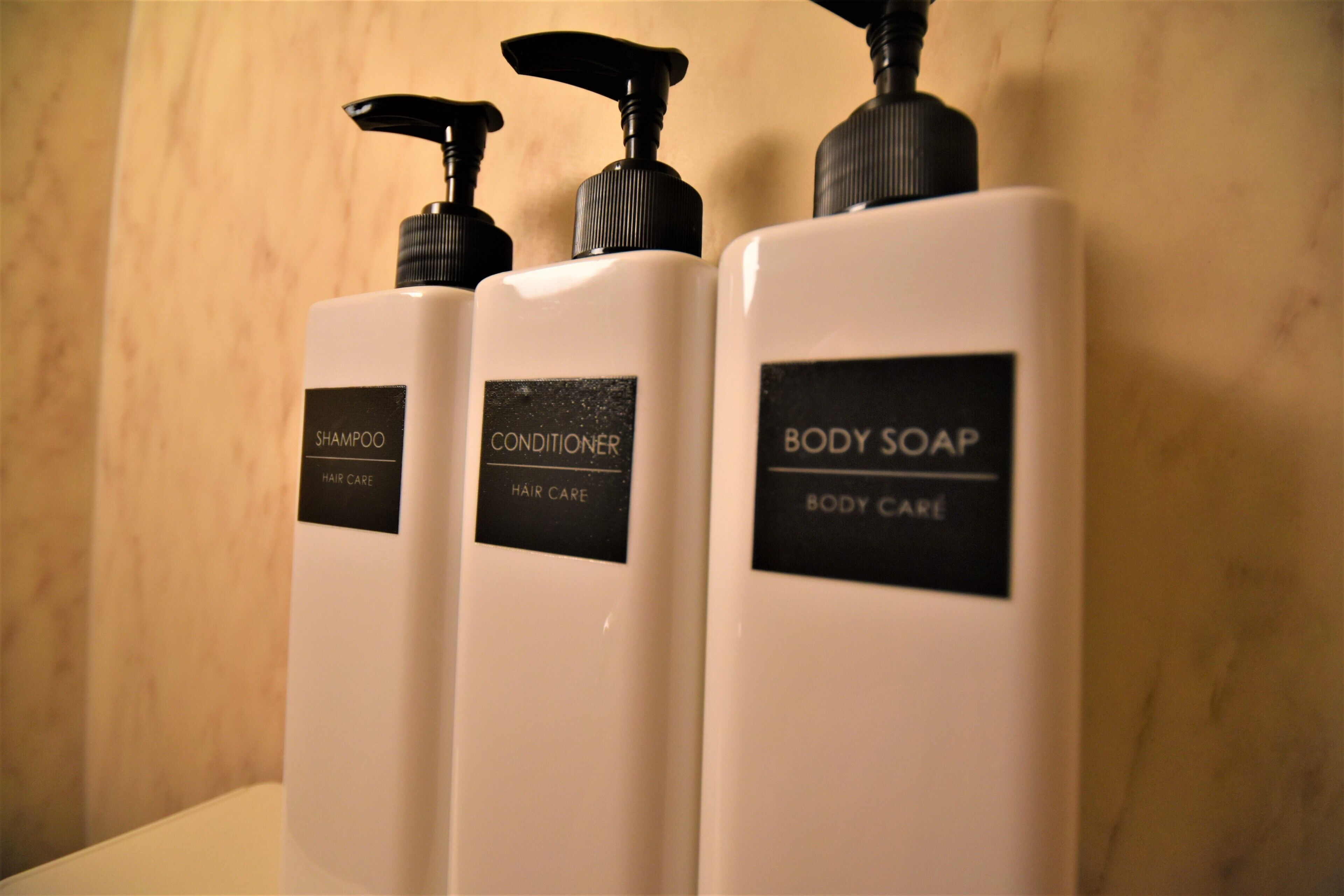 Three white bottles of hair care products with black pumps and labels.