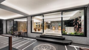 A modern hotel lobby with a reception desk, seating area, and large windows. - Gamalan FL Spring Hotel (Jiaoxi)