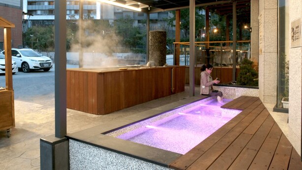 A spa area with a hot tub, wooden benches, and a stone pillar. - Gamalan FL Spring Hotel (Jiaoxi)