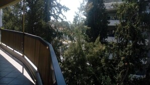 Un balcón con vistas a árboles y un edificio al fondo.