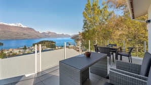 A balcony with wicker furniture, a potted plant, and a view of a lake and mountains. - Deja Vu - Queenstown Holiday Home (Queenstown)