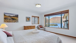 A bedroom with a large bed, a view of a lake, and a mountain in the background. - Deja Vu - Queenstown Holiday Home (Queenstown)