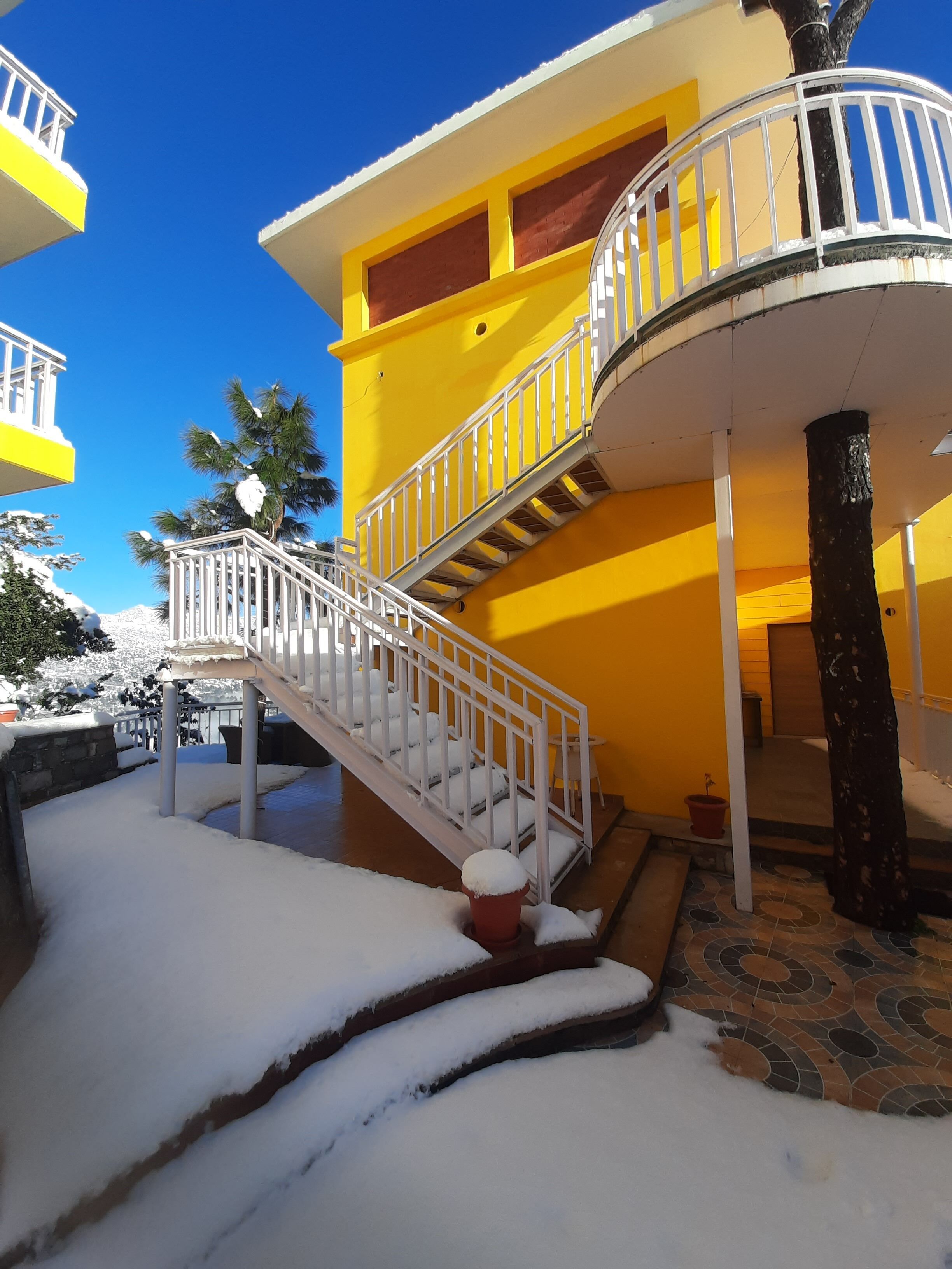 Un bâtiment jaune avec un escalier blanc menant à un balcon.