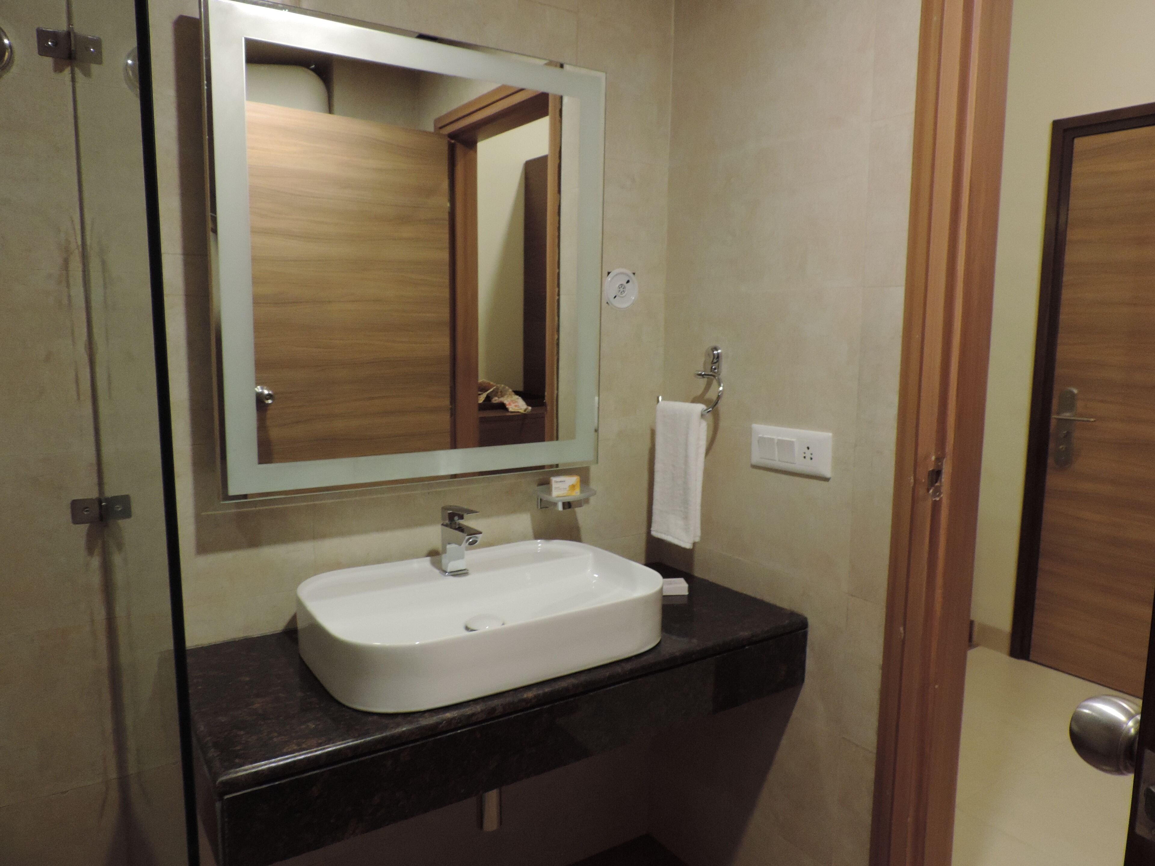 Une salle de bain avec un lavabo blanc, un miroir et une serviette accrochée au mur.