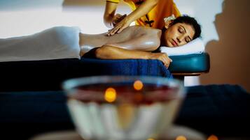 A massage therapy session in a spa setting with a massage table, a towel, and a bowl of candles.
