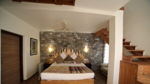 A bedroom with a stone wall, wooden bed, and a wooden staircase. - juSTa Mukteshwar Retreat & Spa (Dhari)