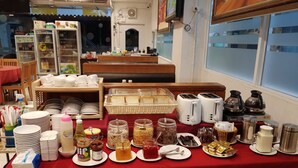 En frukostbuffé med ett varierat utbud av mat, serveringsredskap och en kaffestation.