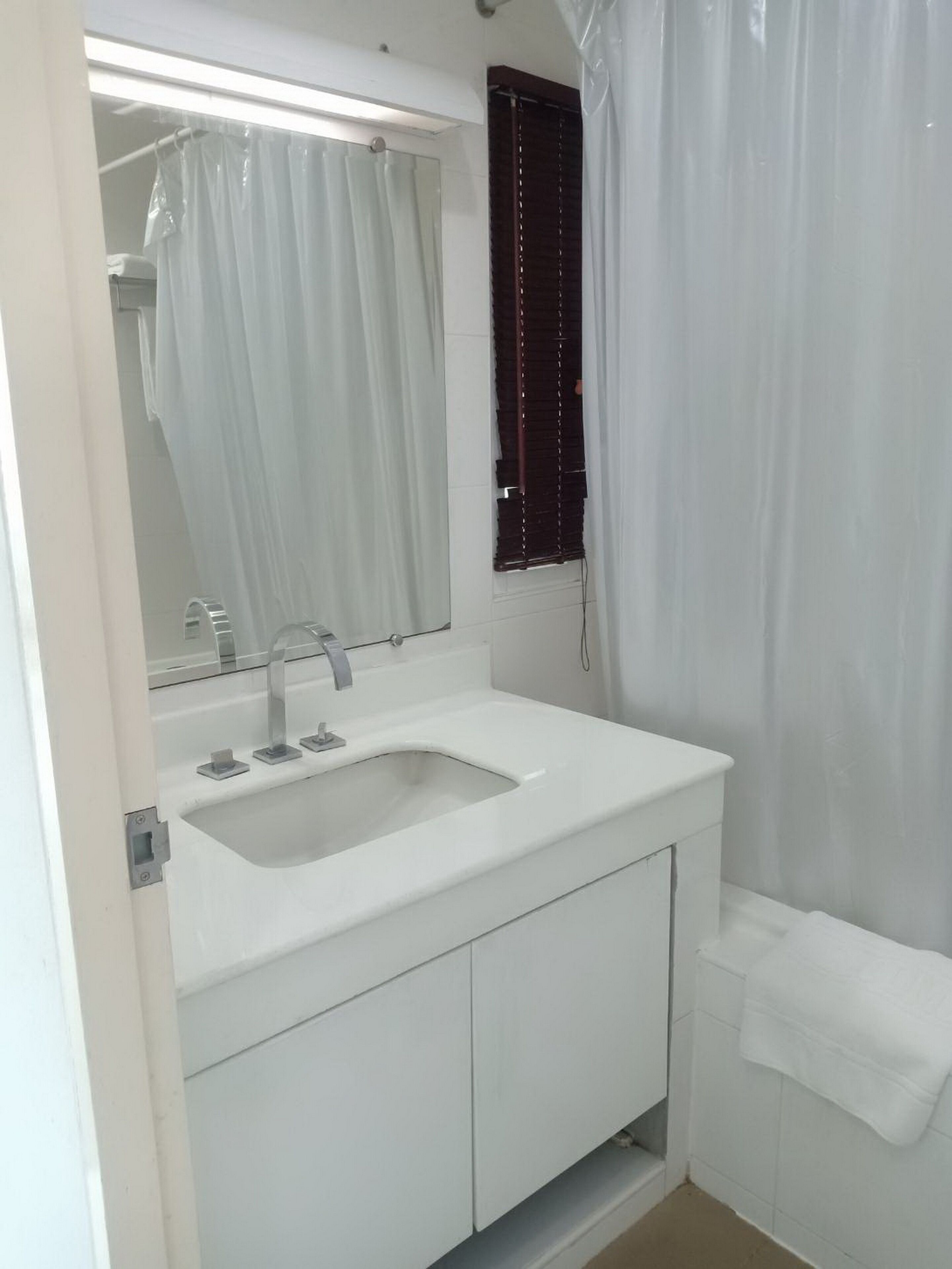 A bathroom with a white sink, mirror, and a shower curtain.