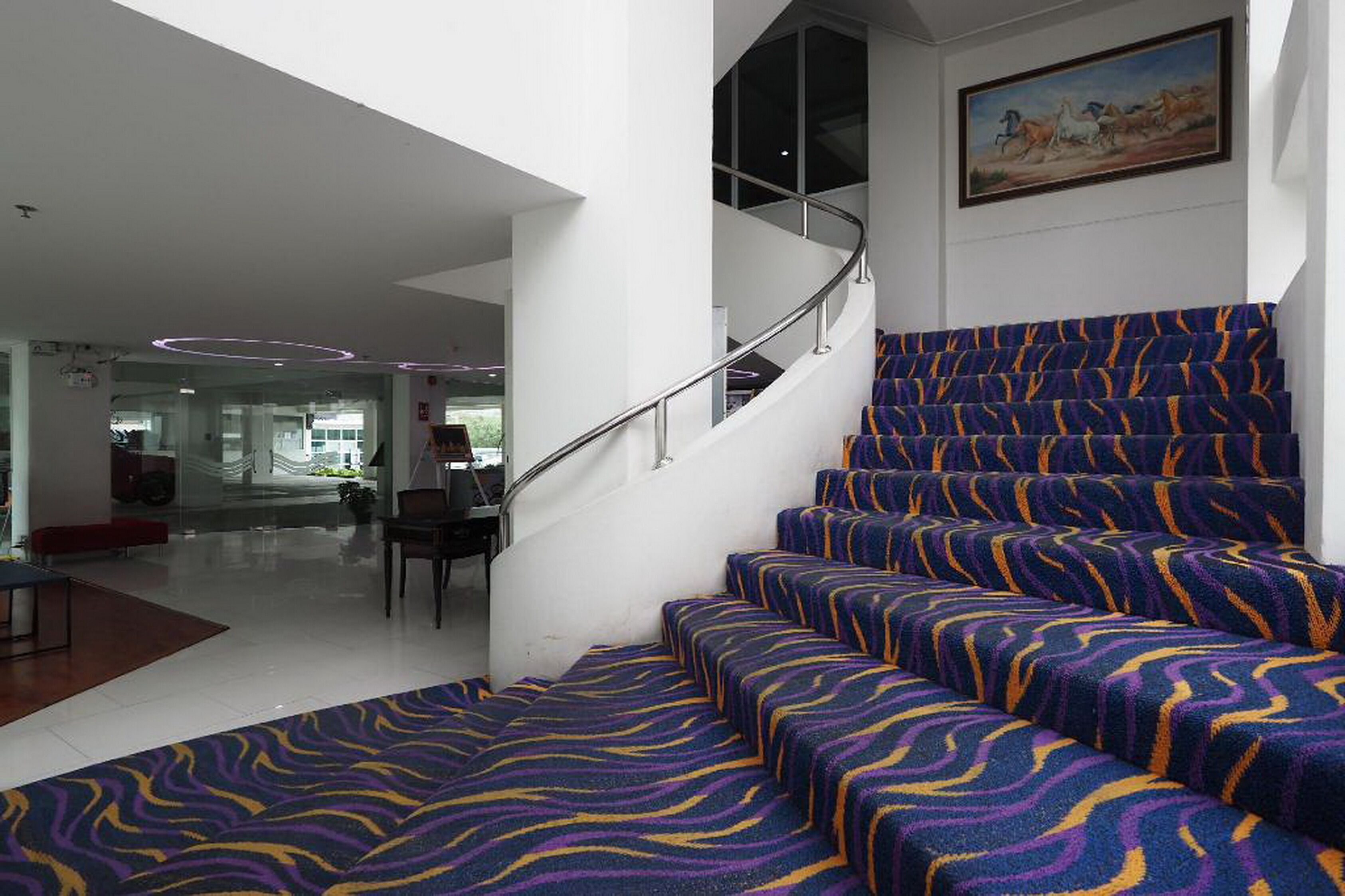 Uma escada com carpete estampado e grades de metal que leva a um andar superior.