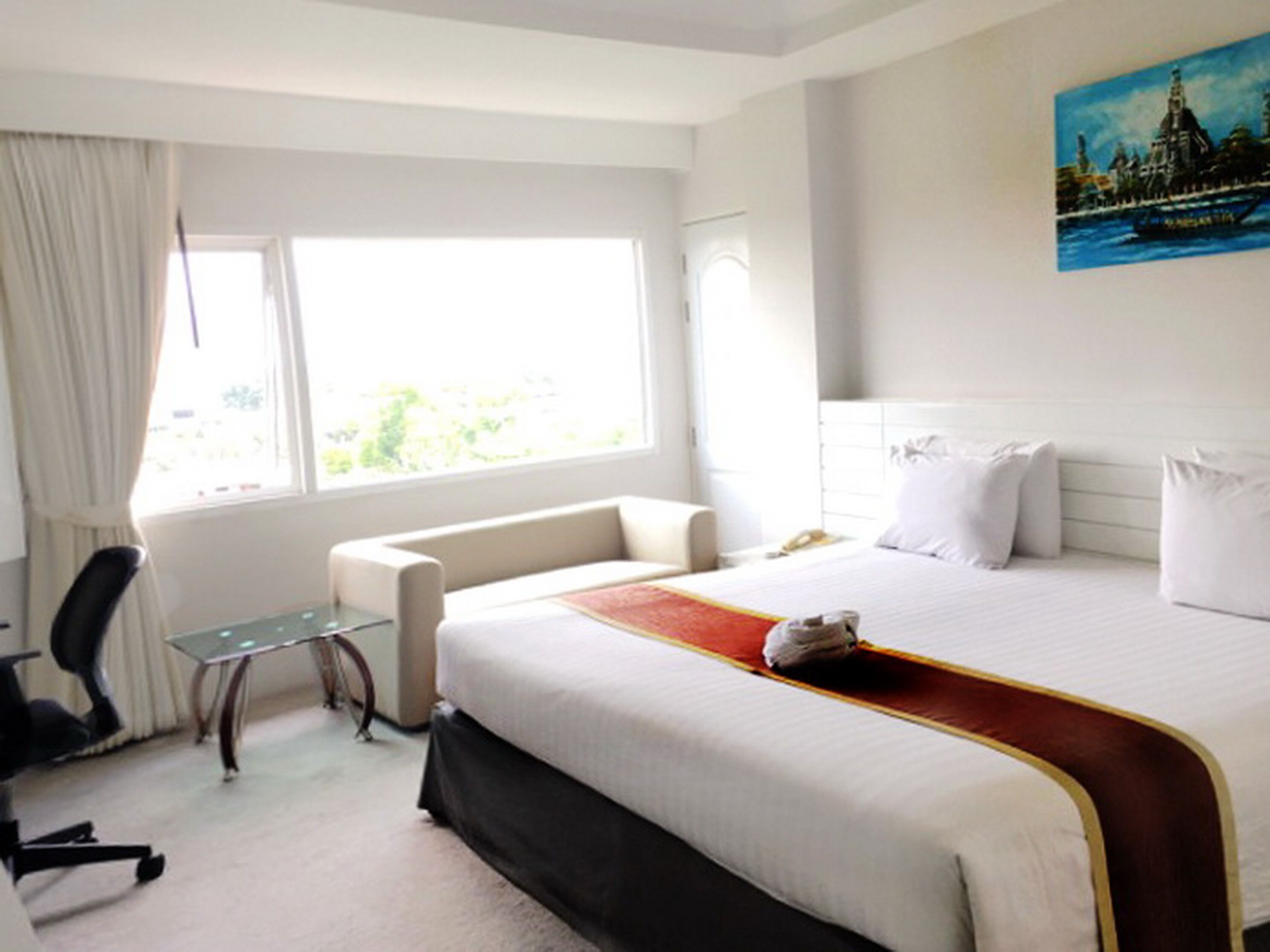 Una habitación de hotel con cama, escritorio, silla y ventana.