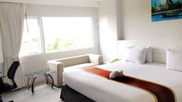 Una habitación de hotel con cama, escritorio, silla y ventana.