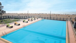 Une piscine avec des chaises longues et vue sur la plage.