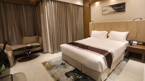 Une chambre d’hôtel moderne avec un grand lit, un canapé, une petite table et une table de chevet avec un téléphone.