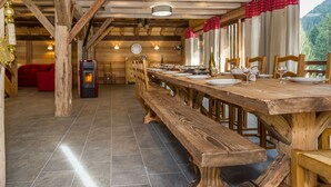 Ein Holzkaminzimmer mit einem langen Esstisch, Bänken und einem Kamin.