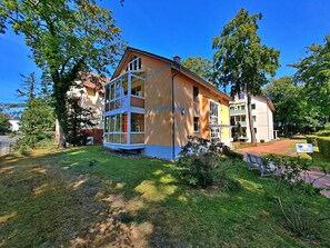 A two-story building with a balcony, surrounded by greenery and trees. - Ostseepark Waterfront Galeone 44 - Galeone 44 (Heringsdorf)