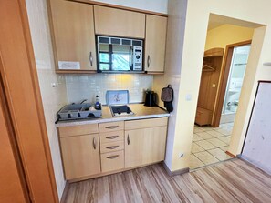 A compact kitchen with a microwave, a kettle, and a toaster. There is a small countertop and cabinets. - Ostseepark Waterfront Galeone 44 - Galeone 44 (Heringsdorf)