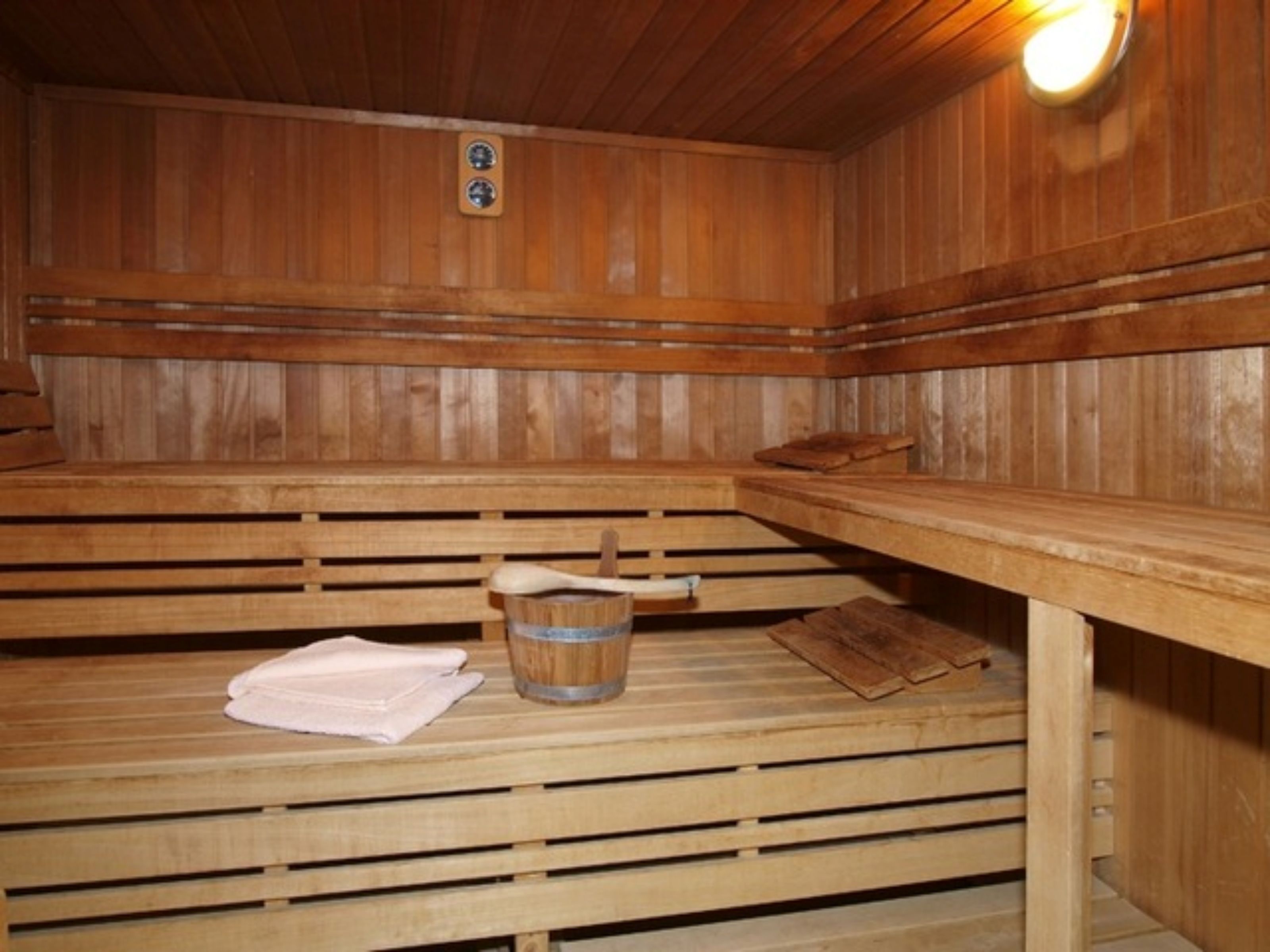 Eine Holzsauna mit Bänken, einem Handtuch und einem Eimer.