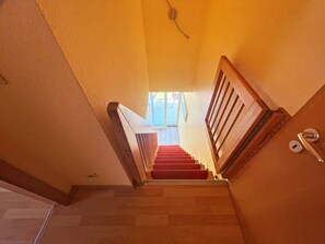 A staircase with wooden railings and red carpeted steps leading to an upper floor. - Ostseepark Waterfront Galeone 44 - Galeone 44 (Heringsdorf)
