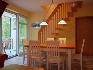 A dining area with a wooden table and chairs, a staircase, and a door. - Ostseepark Waterfront Galeone 44 - Galeone 44 (Heringsdorf)