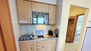 Una cocina compacta equipada con microondas, tetera y tostadora. Dispone de una pequeña encimera y armarios.