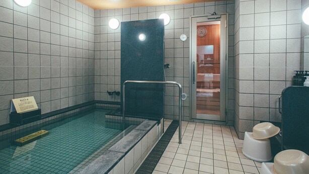 A swimming pool area with tiled walls, a black diving board, and a shower area. - Kuretake Inn Premium Meieki Minami (Nagoya)