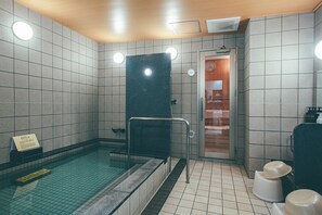 A swimming pool area with tiled walls, a black diving board, and a shower area. - Kuretake Inn Premium Meieki Minami (Nagoya)