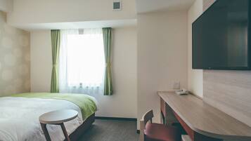 A hotel room with a bed, a desk, a chair, and a television.