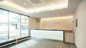 A reception area with a counter, seating, and a clock on the wall. - Kuretake Inn Premium Meieki Minami (Nagoya)