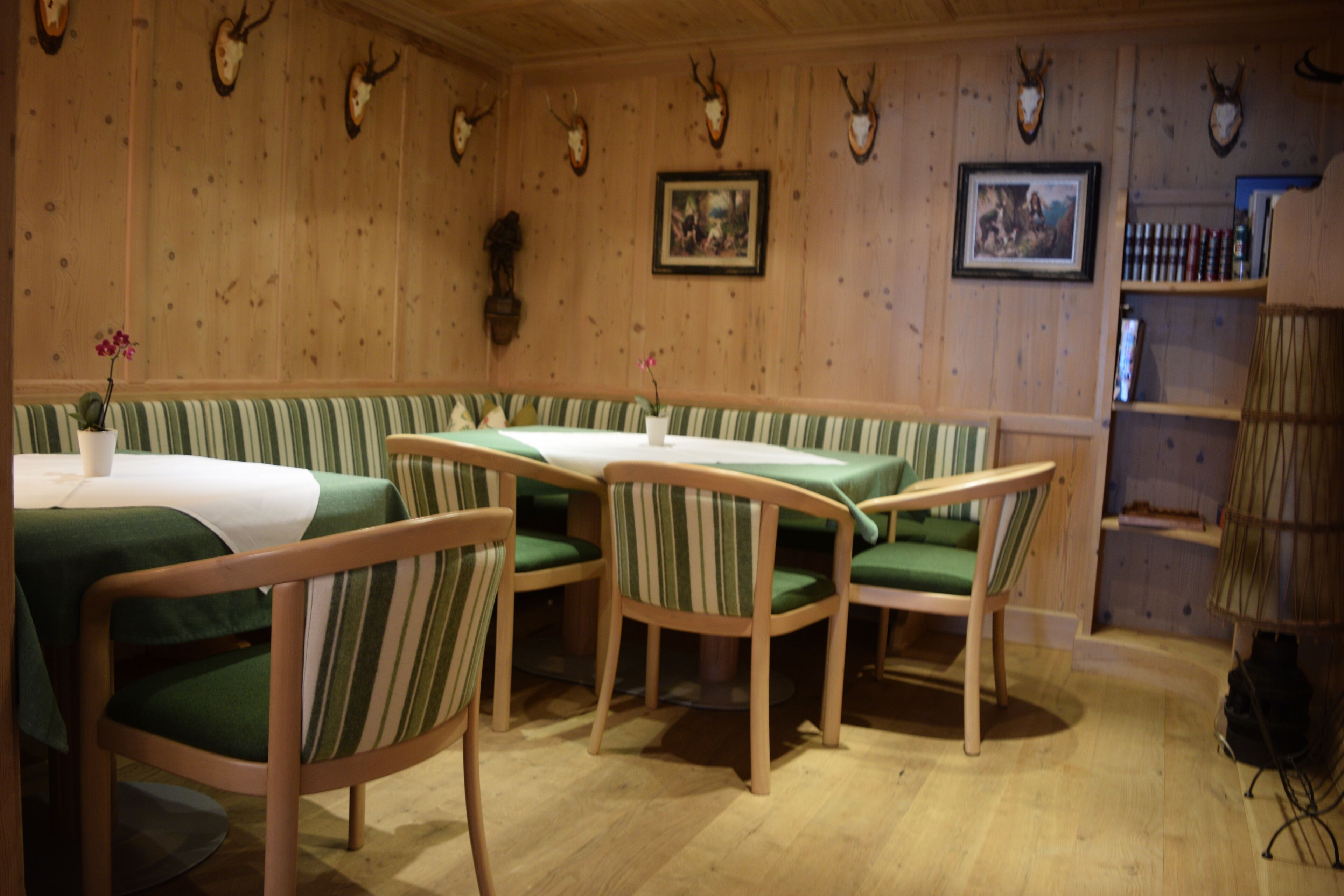 A restaurant with wooden walls, green striped booths, and tables.