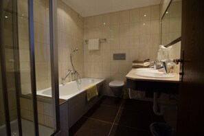 Une salle de bain moderne dotée d’une douche à parois de verre, d’une baignoire, de toilettes et d’un espace lavabo.