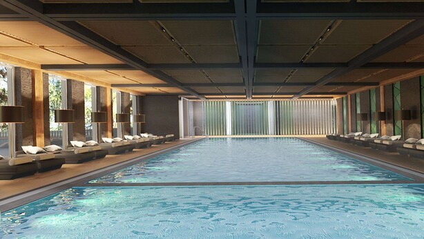 Una amplia piscina cubierta con sillones de descanso y tumbonas a lo largo de los bordes, suelo de baldosas y un diseño moderno en el techo.