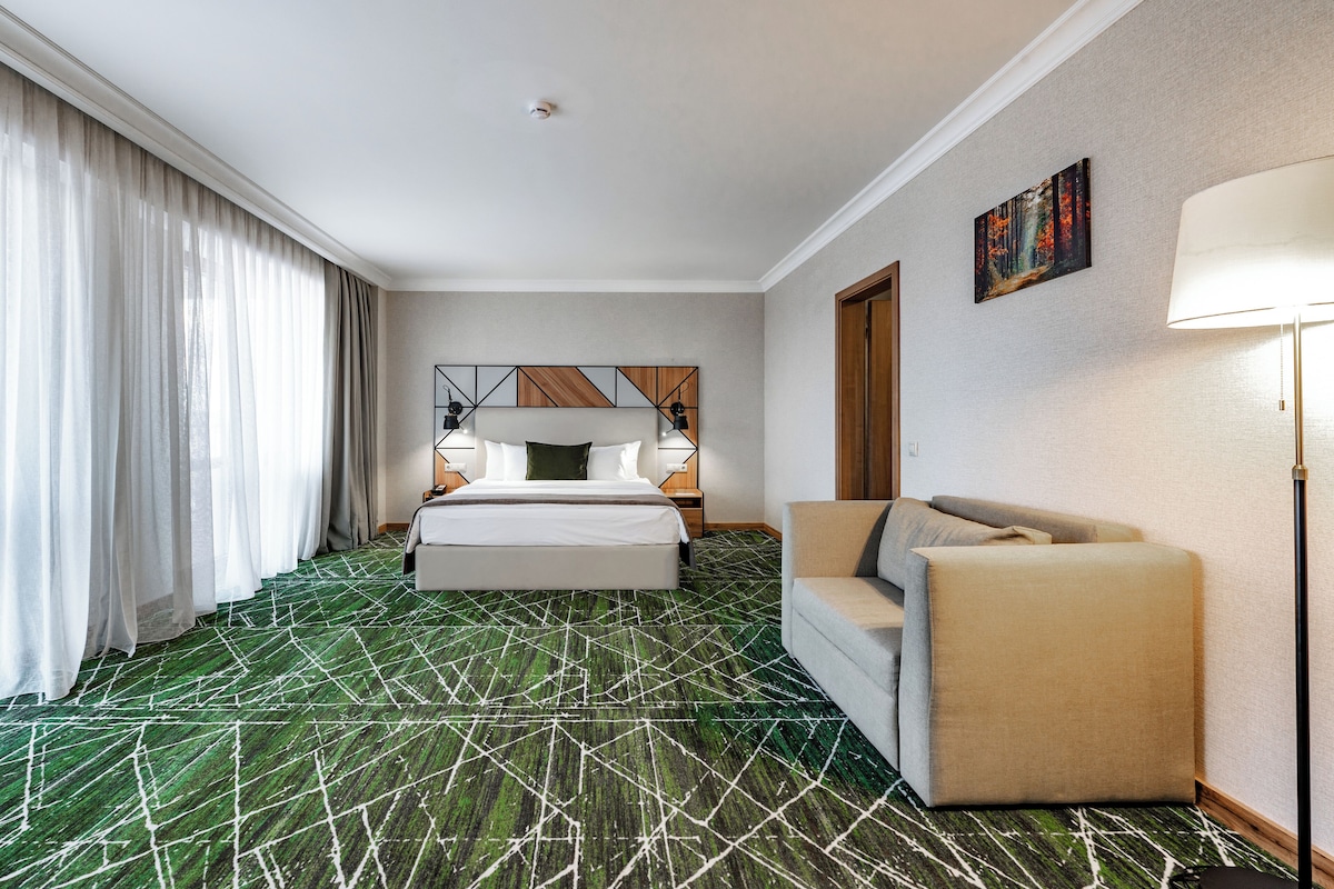 Una habitación de hotel con una cama, un sofá, un cuadro y una lámpara.