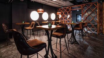 Un interior moderno con mesas redondas y sillones de cuero, separadores de madera e iluminación colgante.